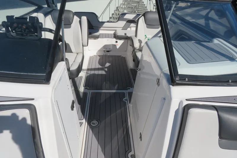Slide: The Image of 2017 Yamaha Boats AR240 bow seating area with gray cushioned surfaces and storage compartments. - 16