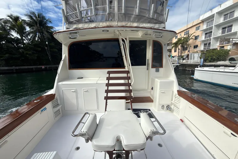 Slide: The Image of 1992 Ocean Yachts 48 Super Sport boat deck with seating and storage, docked near palm trees. - 8