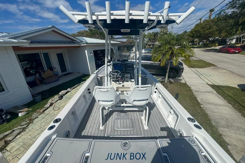 Slide: The Image of 2018 Blue Wave 2400 PureBay boat with center console and seating, parked in a residential area. - 12