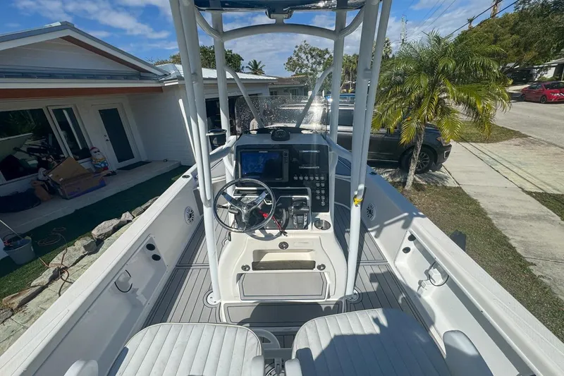 Slide: The Image of 2018 Blue Wave 2400 PureBay boat interior with steering console, parked near a house. - 19