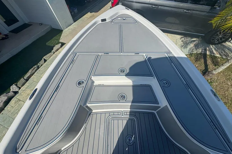 Slide: The Image of 2018 Blue Wave 2400 PureBay boat deck with storage compartments, parked near a house. - 23