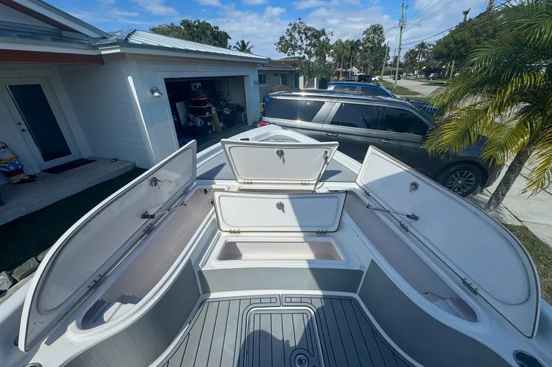 Slide: The Image of 2018 Blue Wave 2400 PureBay boat with open storage compartments in a residential driveway. - 26