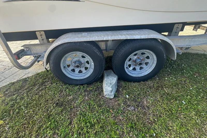 Slide: The Image of Trailer wheels of a 2018 Blue Wave 2400 PureBay boat on grass with a stone block. - 76