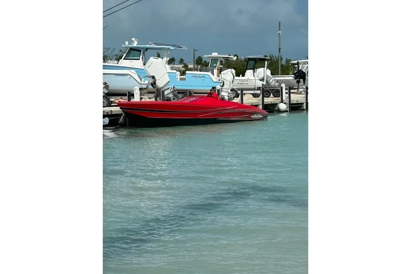 Slide: The Image of 2022 Outerlimits SL41 powerboat, red, docked at marina with yachts in background. - 1