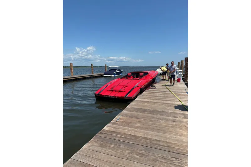 Slide: The Image of Red 2022 Outerlimits SL41 speedboat on a calm river under a partly cloudy sky. - 2