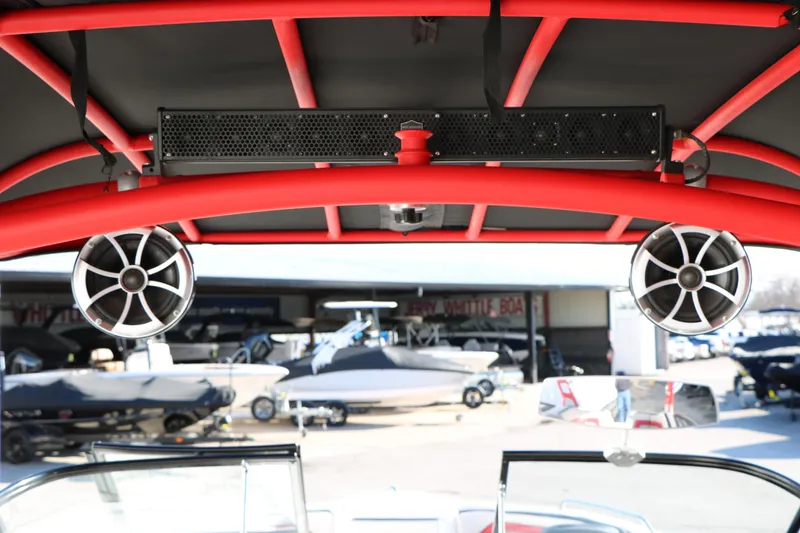 Slide: The Image of 2018 Yamaha Boats 242X E-Series with red frame and speakers, docked at marina. - 18