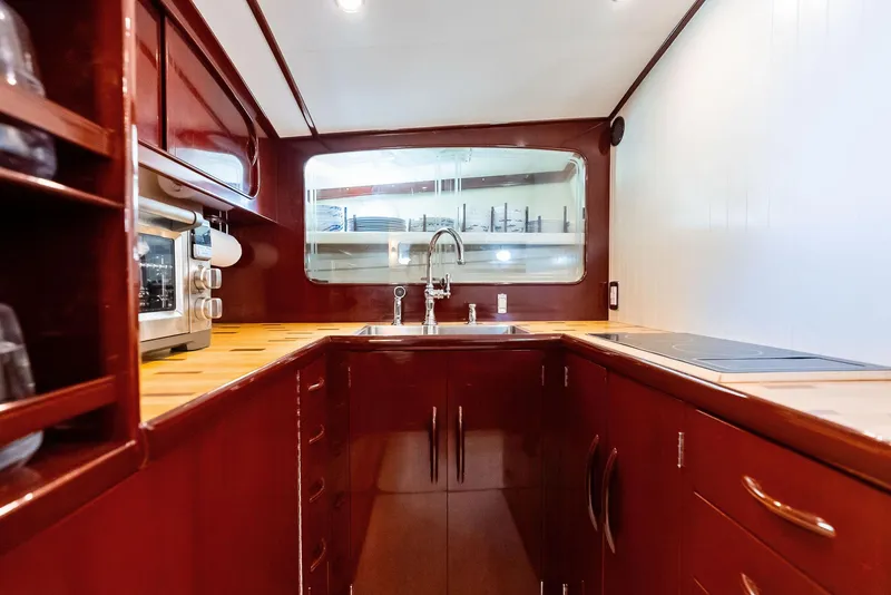Slide: The Image of Luxurious galley kitchen in a 2000 Rybovich Sportfish boat, featuring rich wood cabinetry. - 37