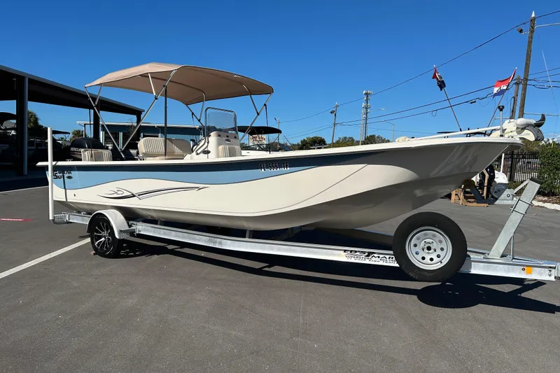 The Image of 2017 Carolina Skiff 258 DLV boat on trailer, beige with canopy, parked outdoors. - 1