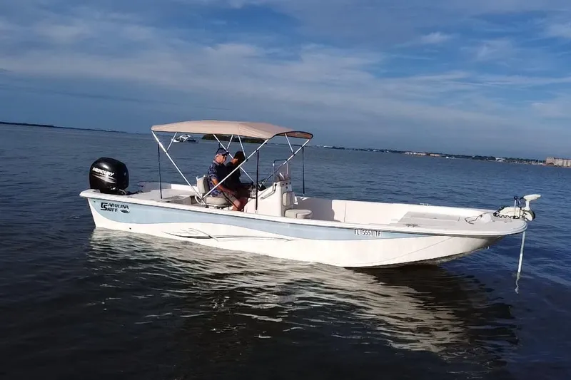 Slide: The Image of 2017 Carolina Skiff 258 DLV boat on calm water with canopy and outboard motor. - 18