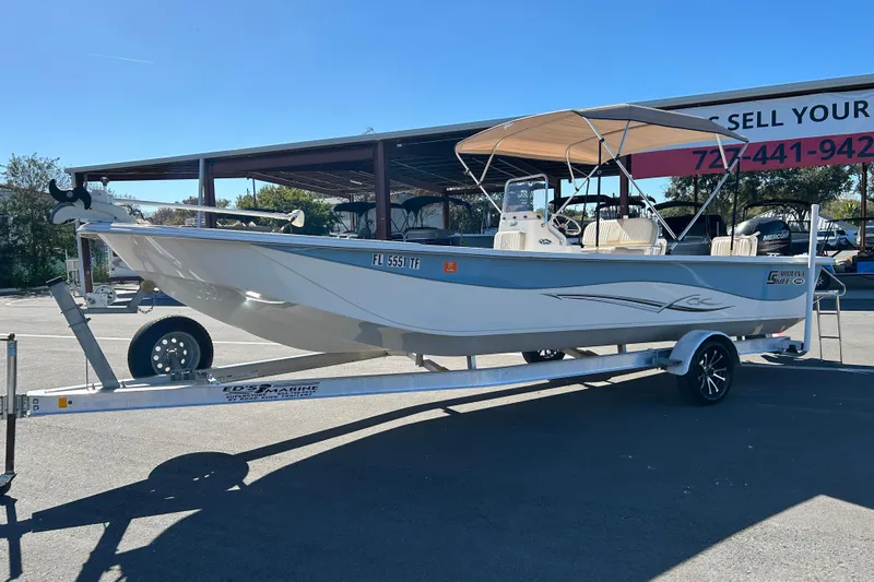 Slide: The Image of 2017 Carolina Skiff 258 DLV boat on trailer, parked outdoors under clear blue sky. - 5