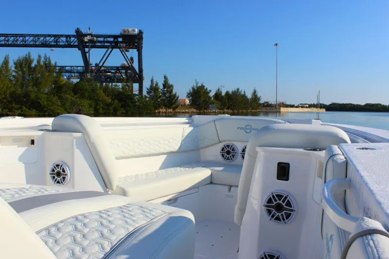 Slide: The Image of 2025 Fountain 38 SCX boat interior with luxurious seating and speakers, docked near a bridge. - 20