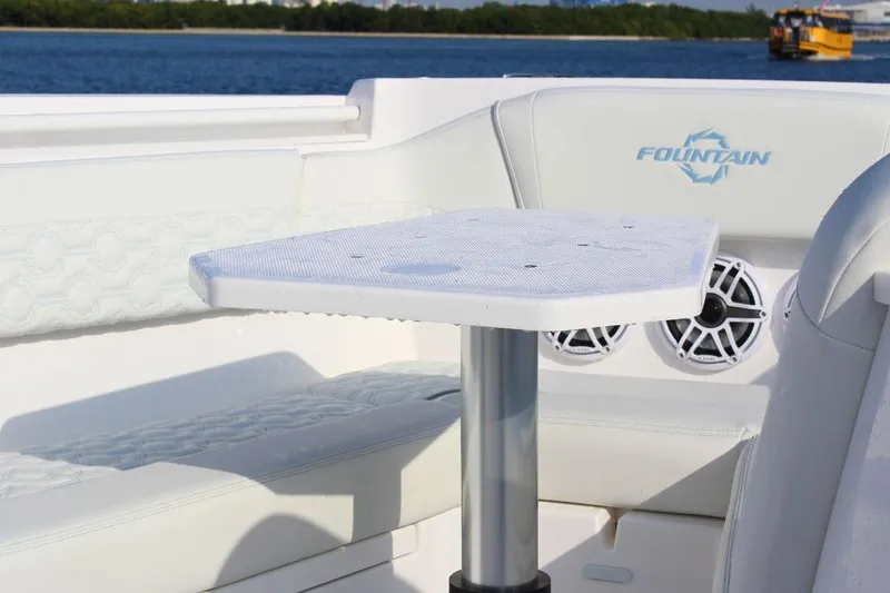 Slide: The Image of 2025 Fountain 38 SCX boat interior with white seating and table, featuring speaker system. - 23