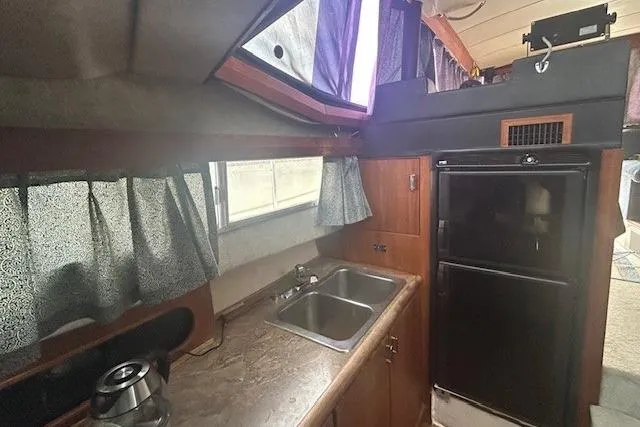 Slide: The Image of 1990 Bayliner 3888 Motoryacht kitchen with sink, fridge, and curtains. - 33