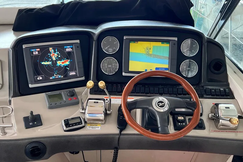 Slide: The Image of 2007 Sea Ray 44 Sundancer helm with navigation screens and wooden steering wheel. - 39