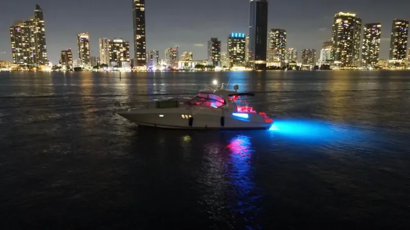 Slide: The Image of 2007 Sea Ray 44 Sundancer yacht illuminated at night with city skyline in the background. - 7