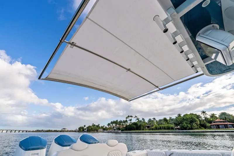 Slide: The Image of 2023 HCB 42 Lujo boat with canopy, scenic waterfront view, blue sky, and lush greenery. - 16