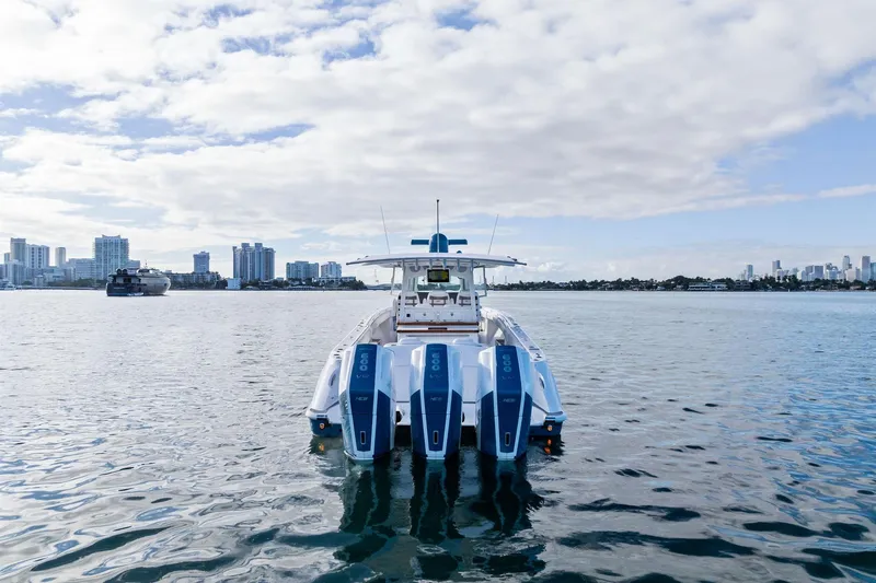 Slide: The Image of 2023 HCB 42 Lujo boat with triple engines on calm water, city skyline in background. - 5