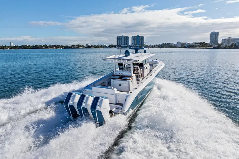 Slide: The Image of 2023 HCB 42 Lujo boat cruising on open water with city skyline in background. - 9