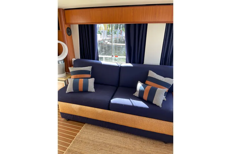 Slide: The Image of 2008 Mainship 34 Trawler Hardtop interior with helm, wicker chair, and large windows. - 19