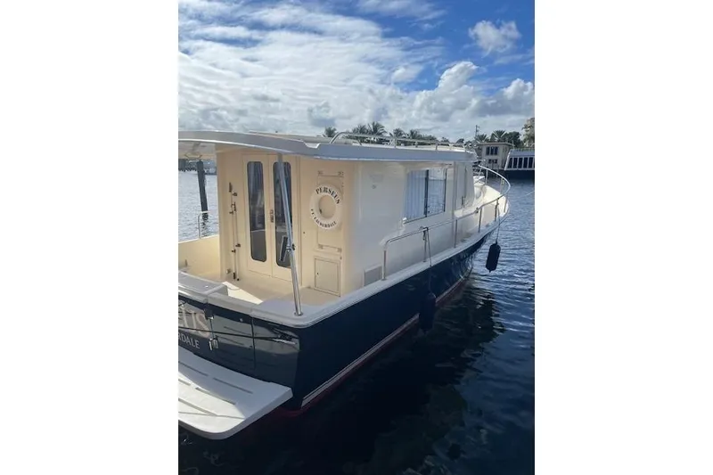 Slide: The Image of 2008 Mainship 34 Trawler Hardtop docked near tropical building and palm trees. - 2