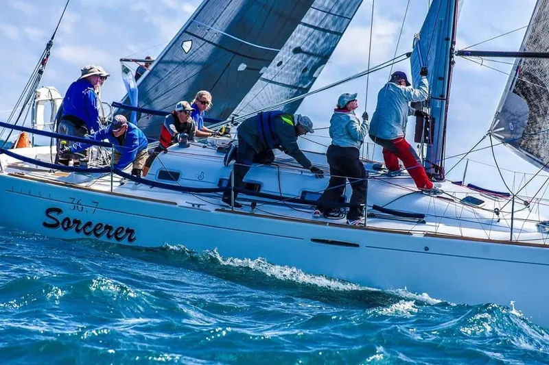 Slide: The Image of Sailors racing on a 2003 Beneteau First 36.7 yacht named "Sorcerer" in open waters. - 1