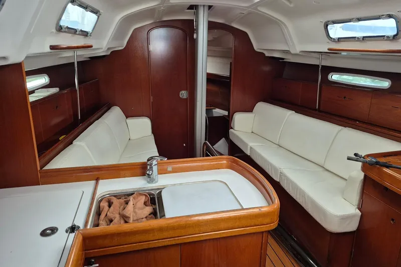 Slide: The Image of Interior of 2003 Beneteau First 36.7 sailboat with wooden table and white seating. - 13