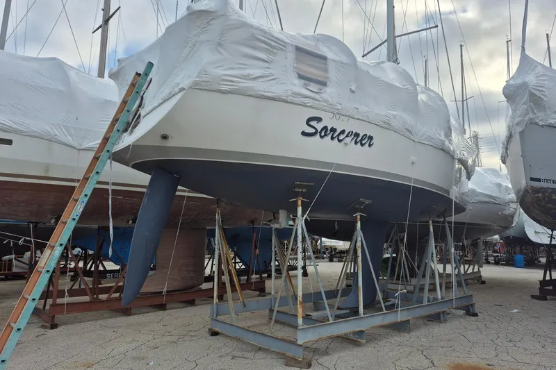 Slide: The Image of 2003 Beneteau First 36.7 sailboat, named "Sorcerer," covered and docked on stands. - 4