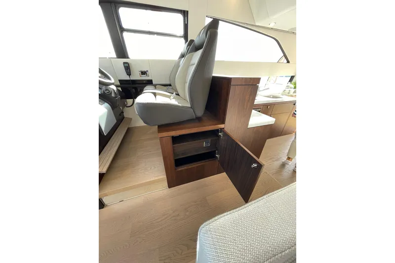 Slide: The Image of Interior of 2025 Fairline Squadron 50 yacht, featuring helm seat and wooden storage cabinet. - 24
