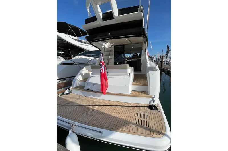 Slide: The Image of 2025 Fairline Squadron 50 yacht with teak deck and red flag, docked at marina. - 7