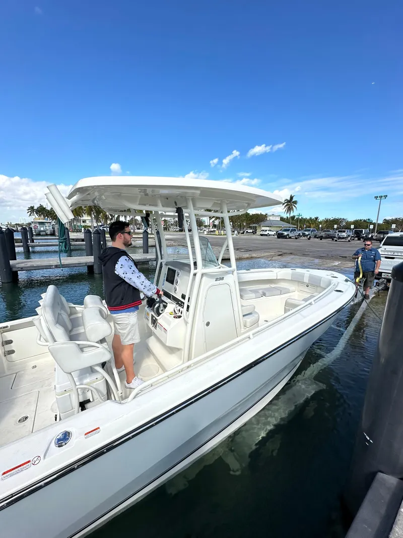 Slide: The Image of 2020 Mako 236 CC boat docked with people onboard under clear blue sky. - 18