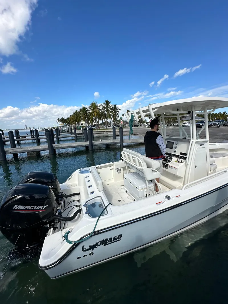 Slide: The Image of 2020 Mako 236 CC boat with Mercury engine, docked near palm trees under blue sky. - 19