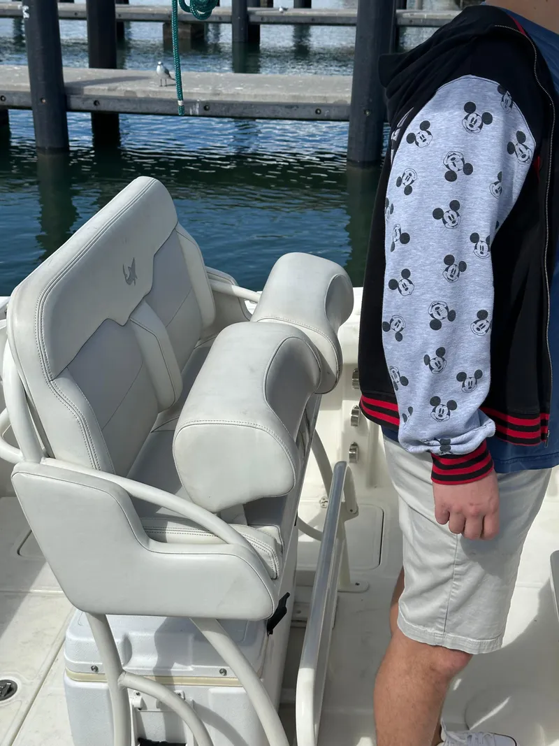 Slide: The Image of 2020 Mako 236 CC boat interior with white seating, person in Mickey Mouse jacket. - 21