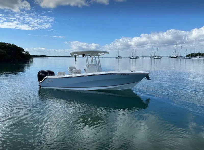 Slide: The Image of 2020 Mako 236 CC boat on calm water with sailboats in the background. - 4