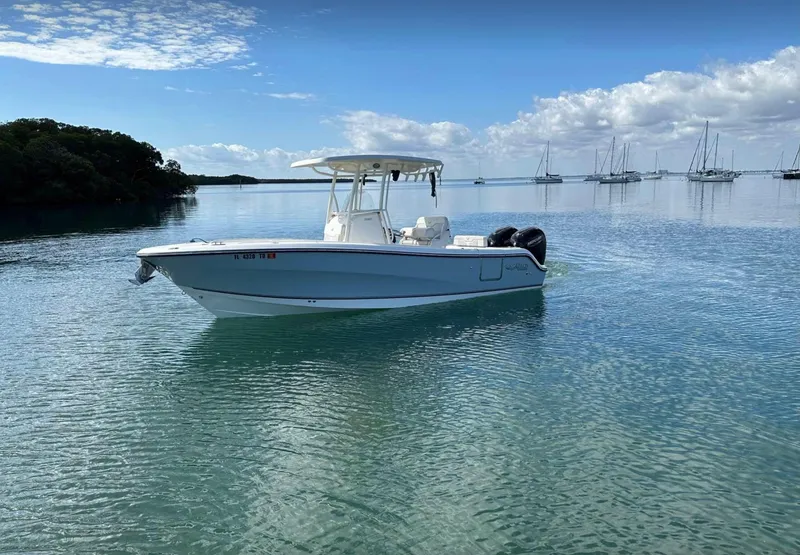 Slide: The Image of 2020 Mako 236 CC boat on calm water with sailboats in the background. - 5