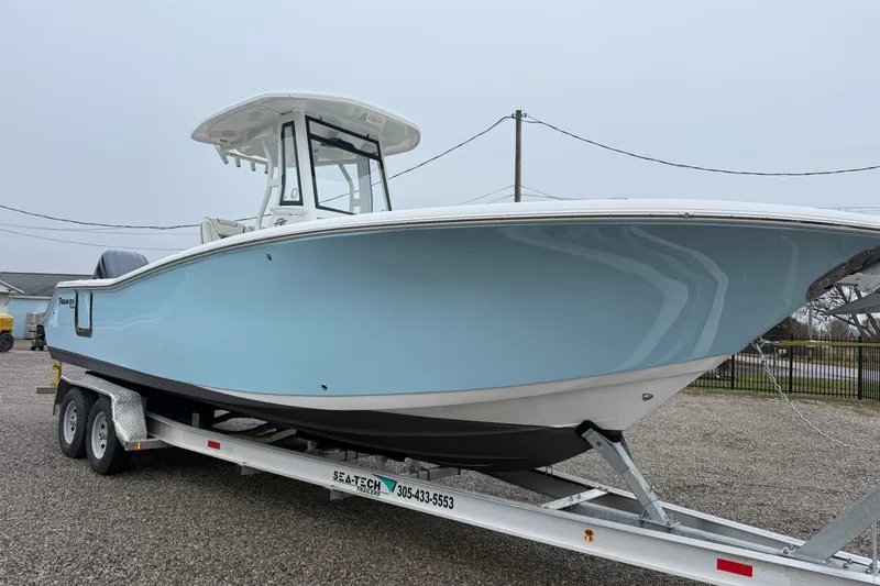 The Image of 2022 Tidewater 272 CC Adventure boat on trailer, light blue hull, parked outdoors. - 1