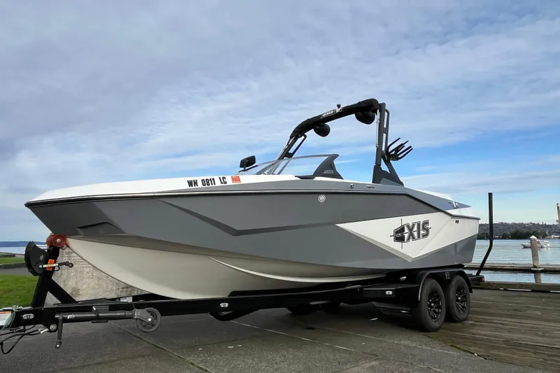 Slide: The Image of 2024 Axis T220 boat on trailer by waterfront, under cloudy sky. - 16