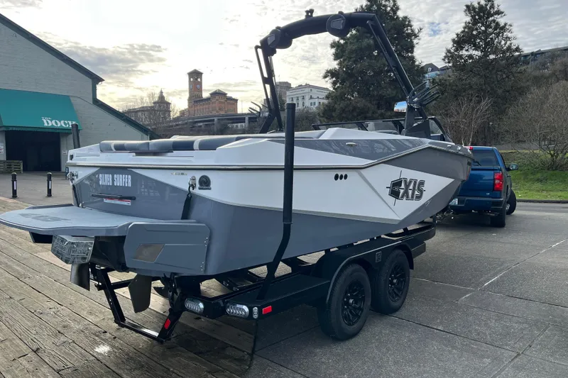 Slide: The Image of 2024 Axis T220 boat on trailer, parked near a dock with urban background. - 21