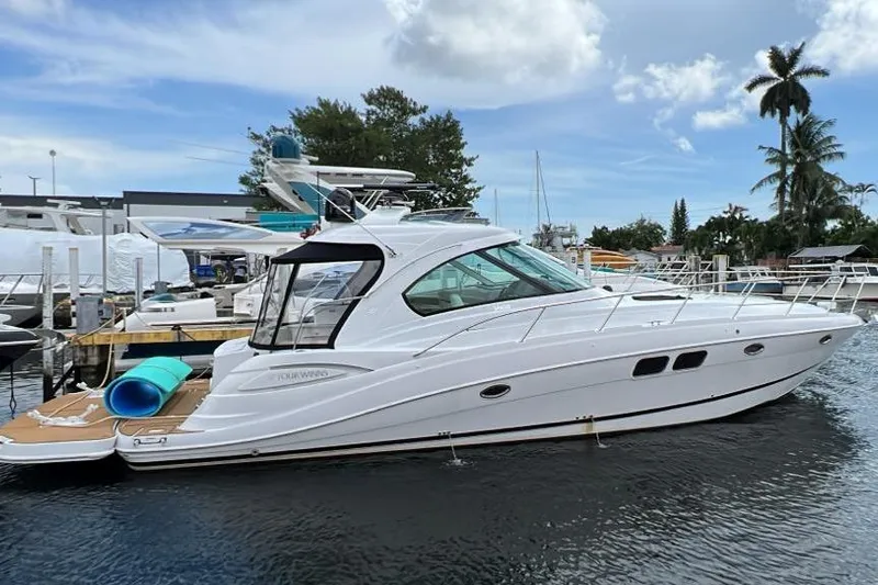 Slide: The Image of 2009 Four Winns V458 yacht docked in marina, sleek white design, calm water, clear sky. - 11