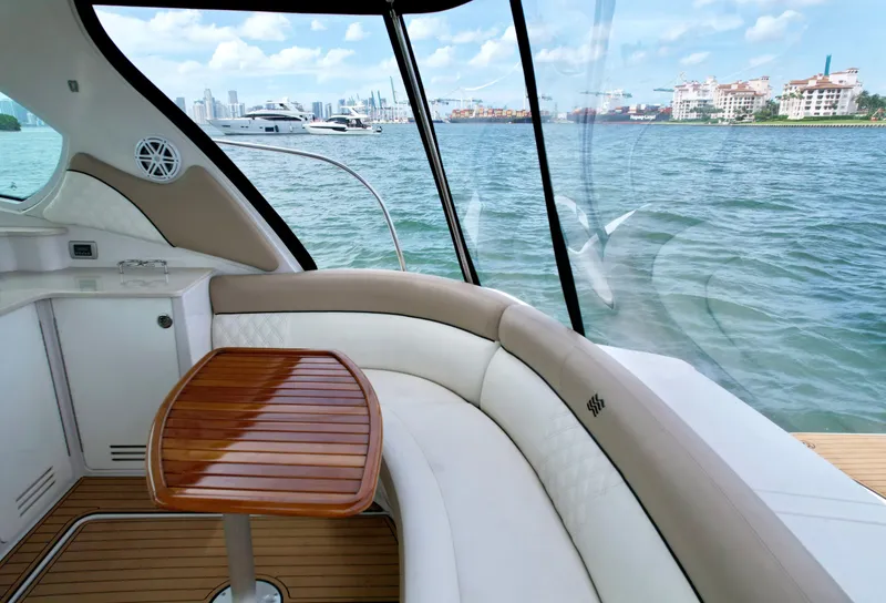 Slide: The Image of 2009 Four Winns V458 yacht interior with curved seating and wooden table, overlooking scenic waterfront. - 21