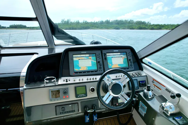 Slide: The Image of 2009 Four Winns V458 yacht cockpit with navigation screens and steering wheel, cruising on open water. - 22