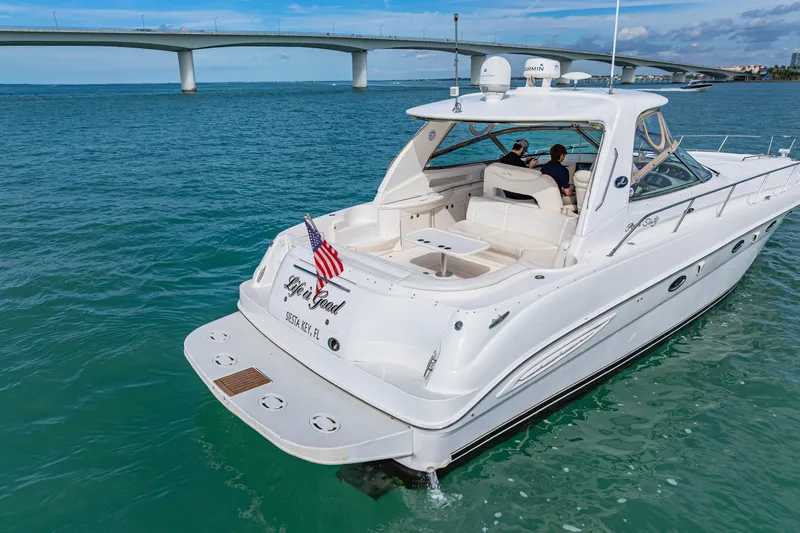 Slide: The Image of 2002 Sea Ray 460 Sundancer yacht cruising under a bridge in clear blue waters. - 37