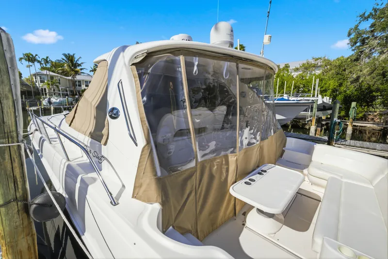 Slide: The Image of 2002 Sea Ray 460 Sundancer yacht docked, featuring a covered seating area and clear canopy. - 48