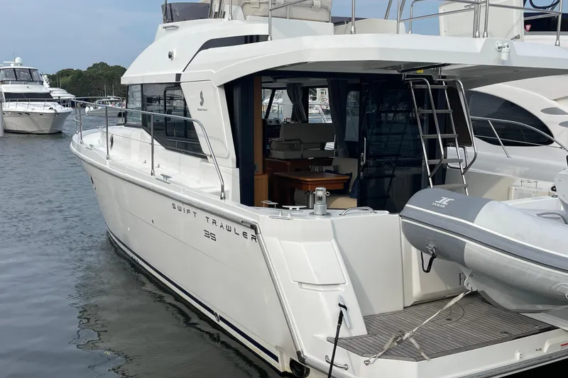 Slide: The Image of 2018 Beneteau Swift Trawler 35 docked, showcasing sleek design and spacious deck area. - 2