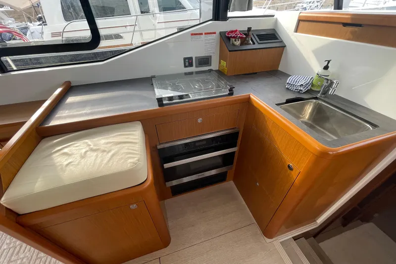 Slide: The Image of 2018 Beneteau Swift Trawler 35 kitchen with stove, sink, and wooden cabinetry. - 21