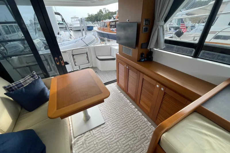 Slide: The Image of 2018 Beneteau Swift Trawler 35 interior with wooden table, seating, and marina view. - 29