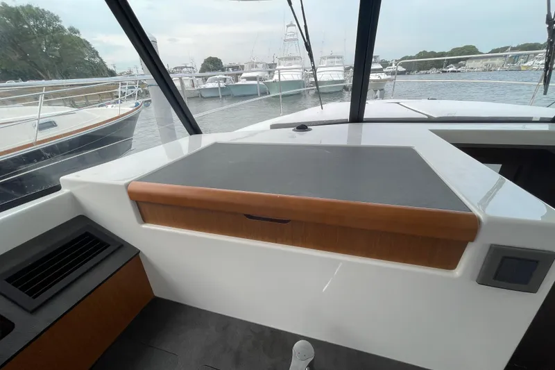 Slide: The Image of 2018 Beneteau Swift Trawler 35 helm station with marina view in the background. - 46