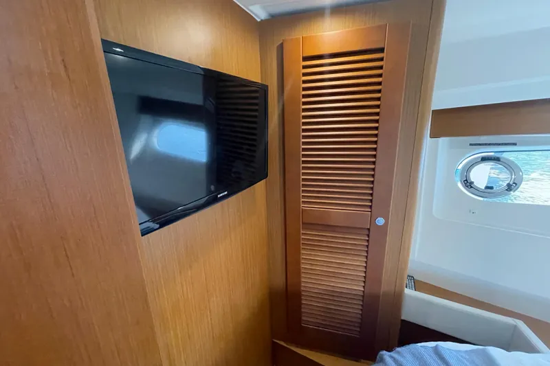 Slide: The Image of 2018 Beneteau Swift Trawler 35 interior with TV, wooden paneling, and porthole window. - 62