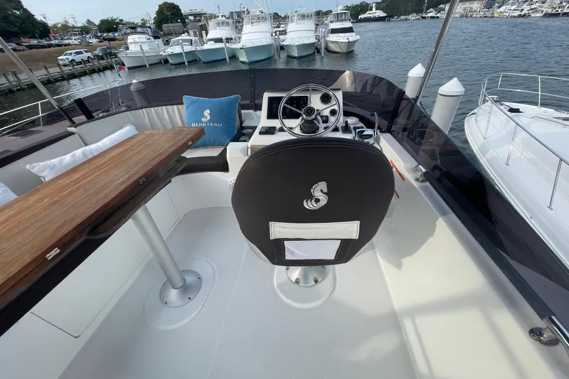 Slide: The Image of 2018 Beneteau Swift Trawler 35 helm with steering wheel, wooden table, and branded cushion. - 84