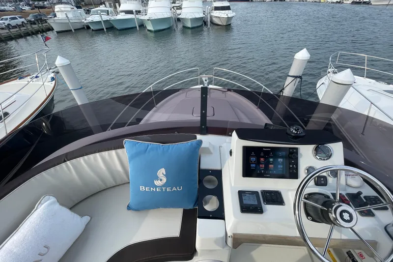 Slide: The Image of 2018 Beneteau Swift Trawler 35 helm with navigation controls and branded cushion, docked at marina. - 89