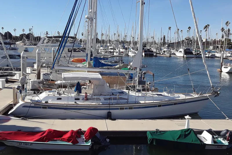 Slide: The Image of 1991 Taswell Sloop docked at a marina, surrounded by other boats and clear blue skies. - 1